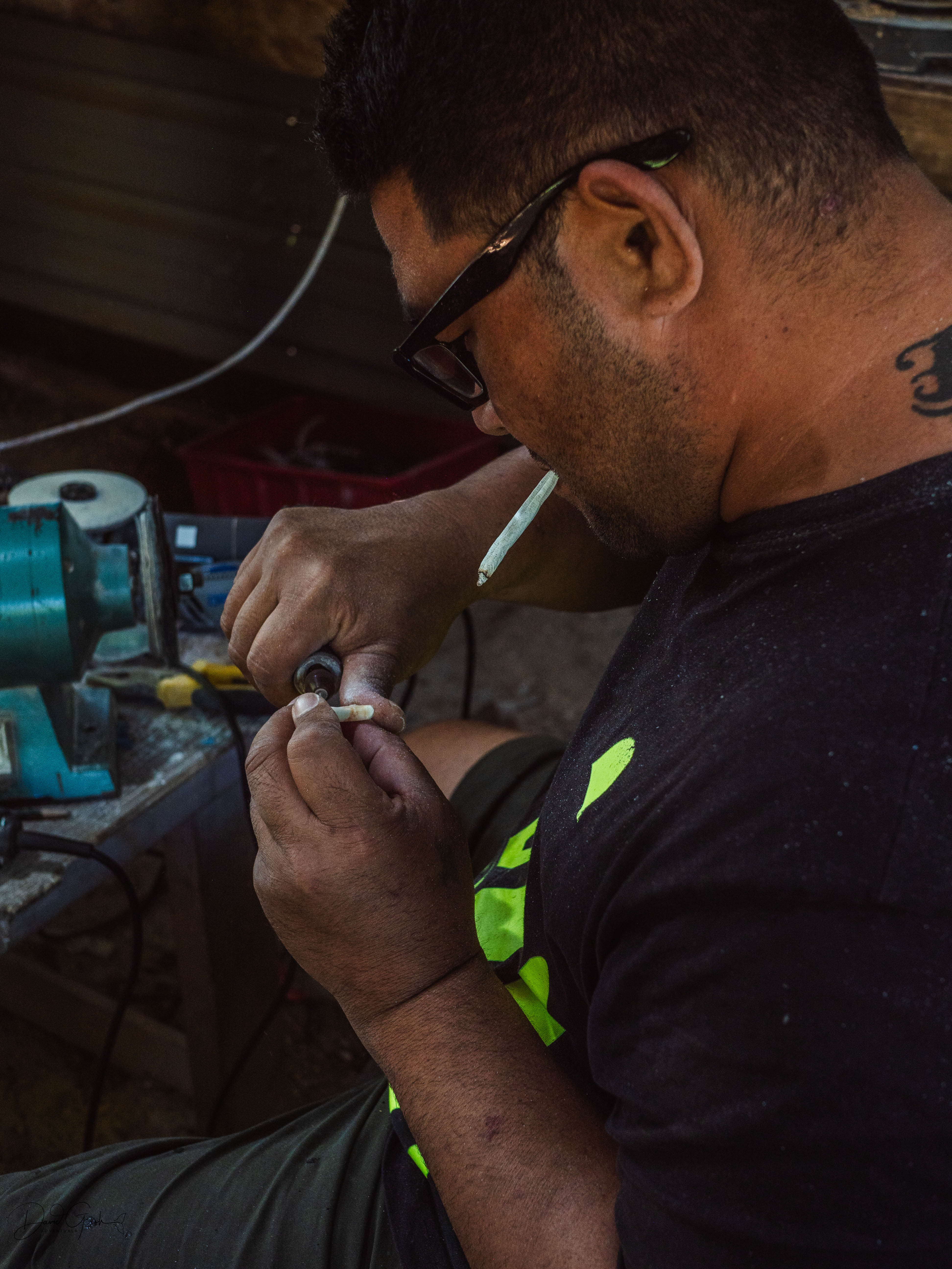 Over-shoulder view of Sione carving detail work into whale bone