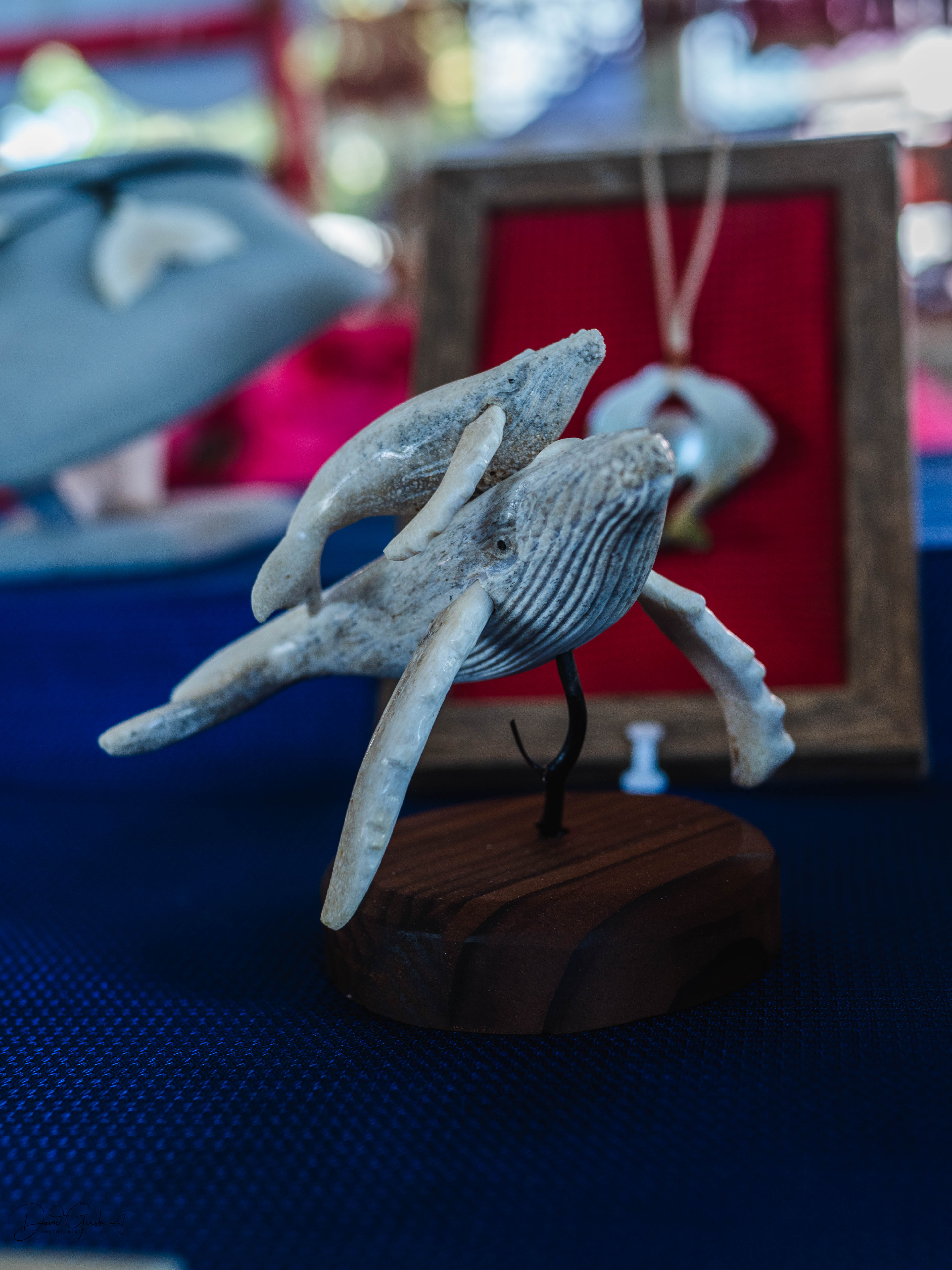 Carved whale bone humpback sculpture on wooden stand at the market