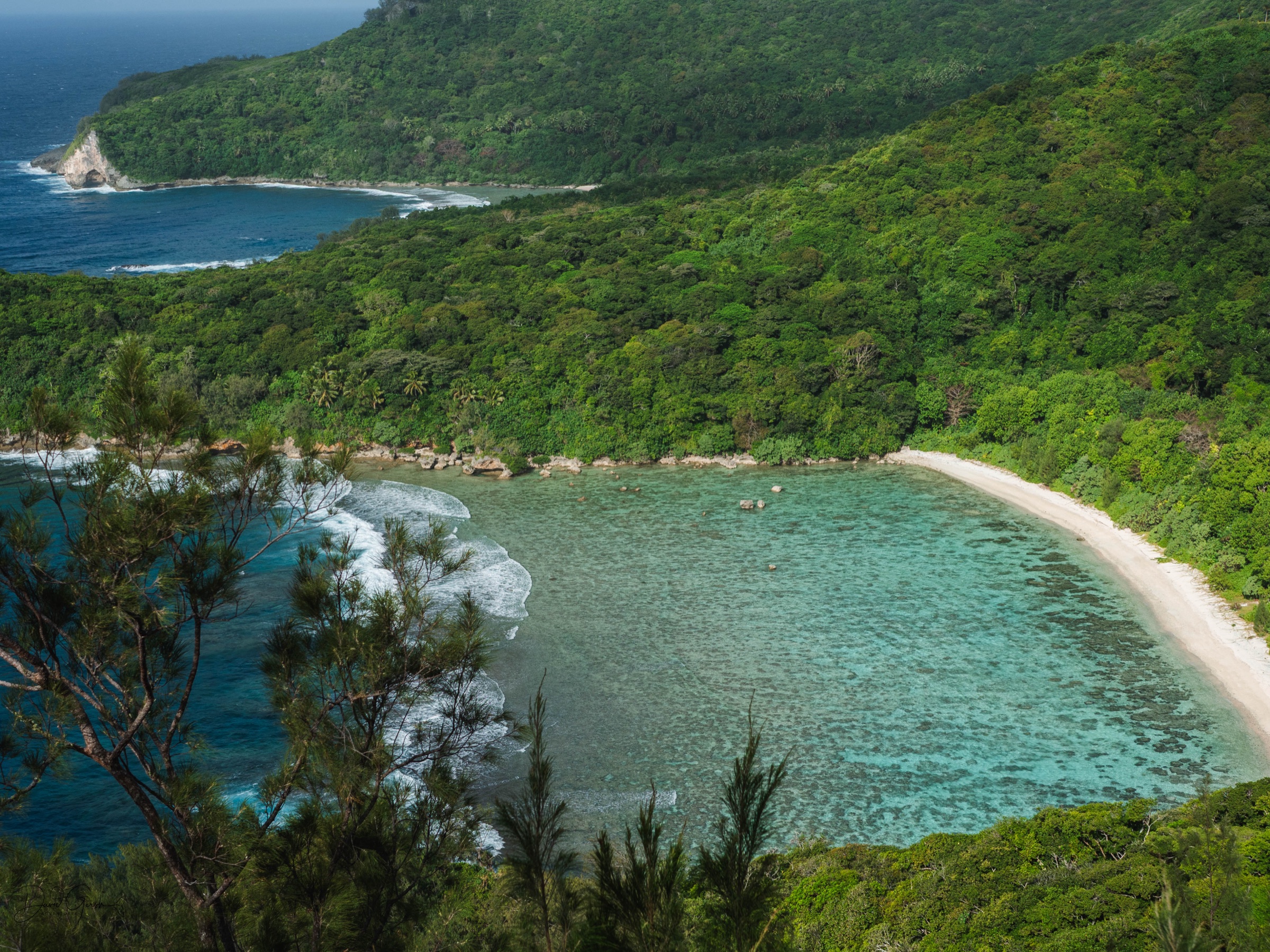 Elevated view over a sheltered turquoise cove and white sand beach in the Vava'u island group